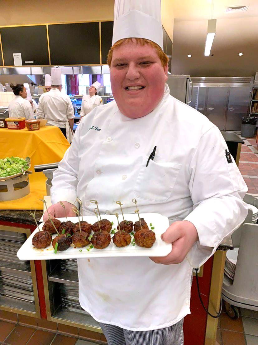 Chef Josh Fried in white coat holding tray of meatballs