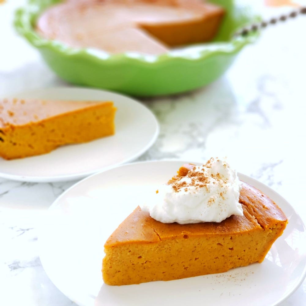 Slice of Pumpkin Impossible Pie on a white plate with a green pie dish in the background