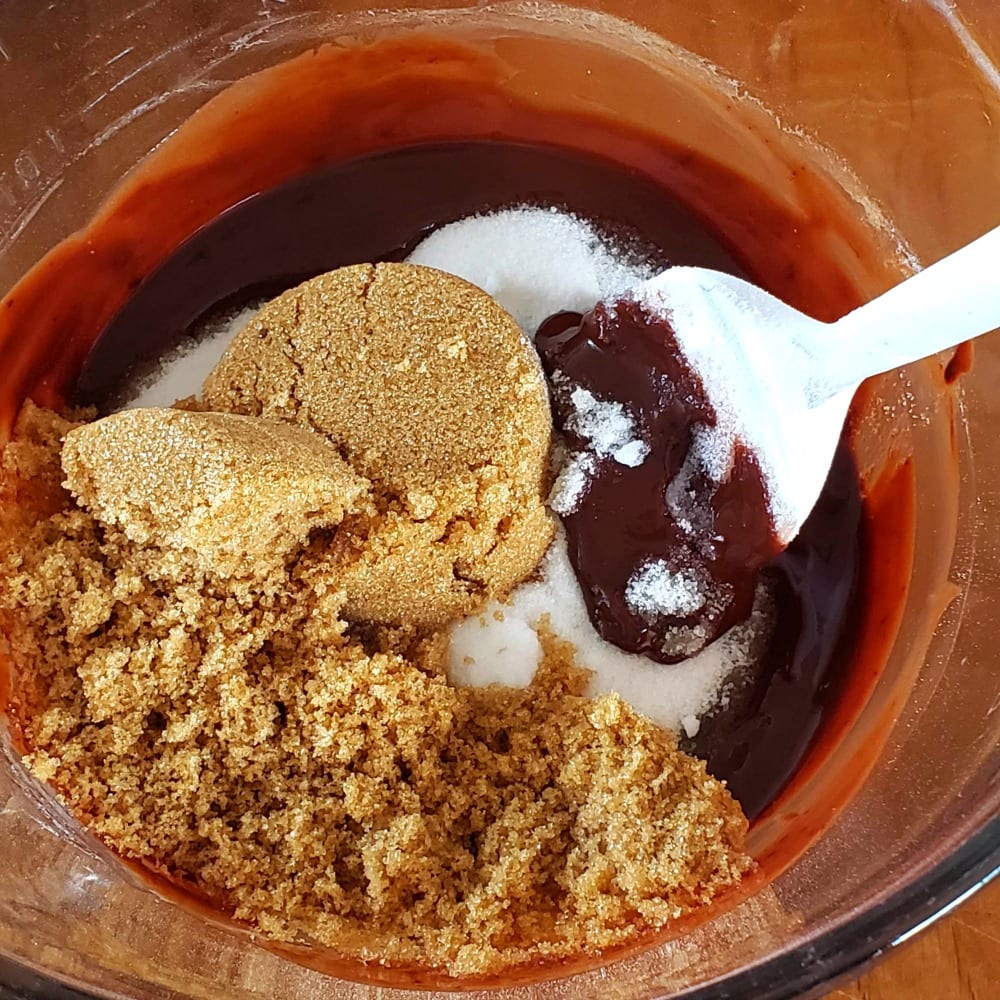 Sugars added to the melted butter and chocolate with a white spoon