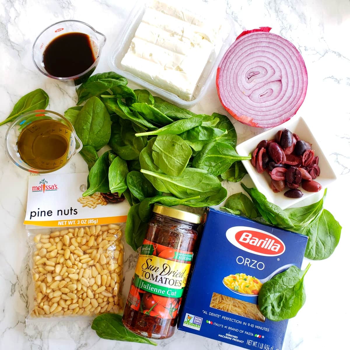 Ingredients for Spinach Orzo Salad on a white marble counter