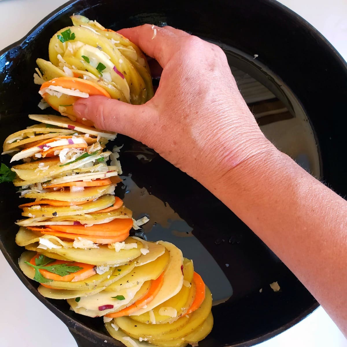 Stack potatoes on their sides in the skillet for Cheese Herb Potato Gratin