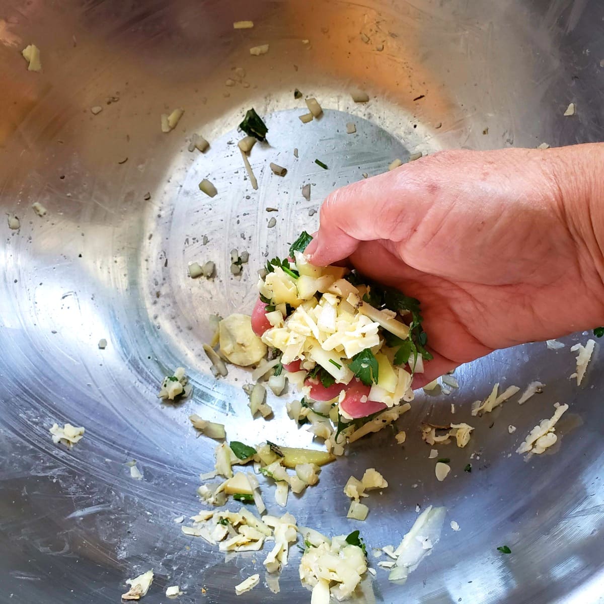 Hand scraping up all the leftover filling from the big metal mixing bowl