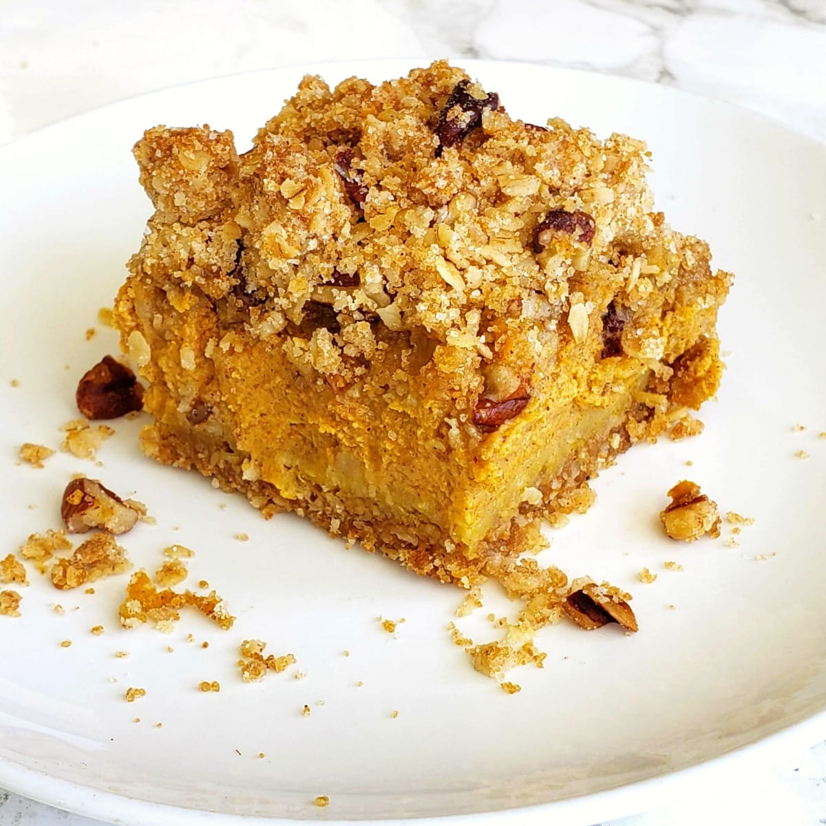 Pumpkin Pie Bars with Oat Crumble Topping on a white plate on a marble counter