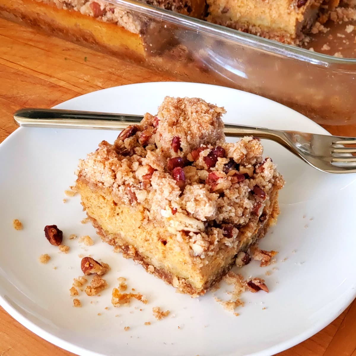 Pumpkin Pie Bars with Oat Crumble on a white plate with a fork behind the piece