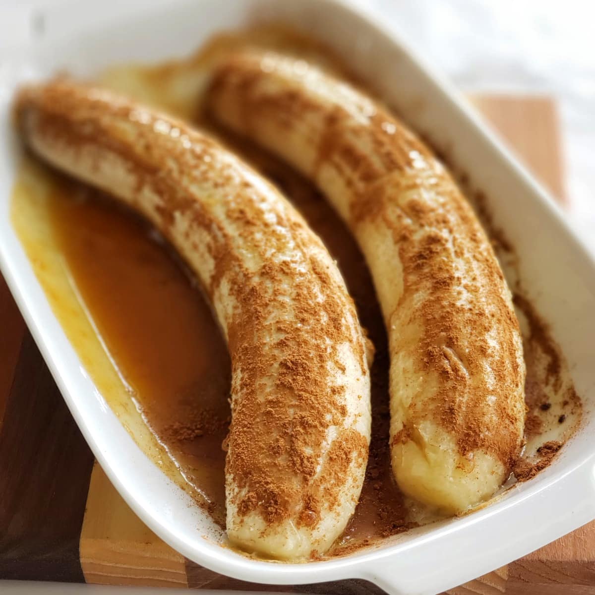 Bananas in a white dish after baking with cinnamon on top