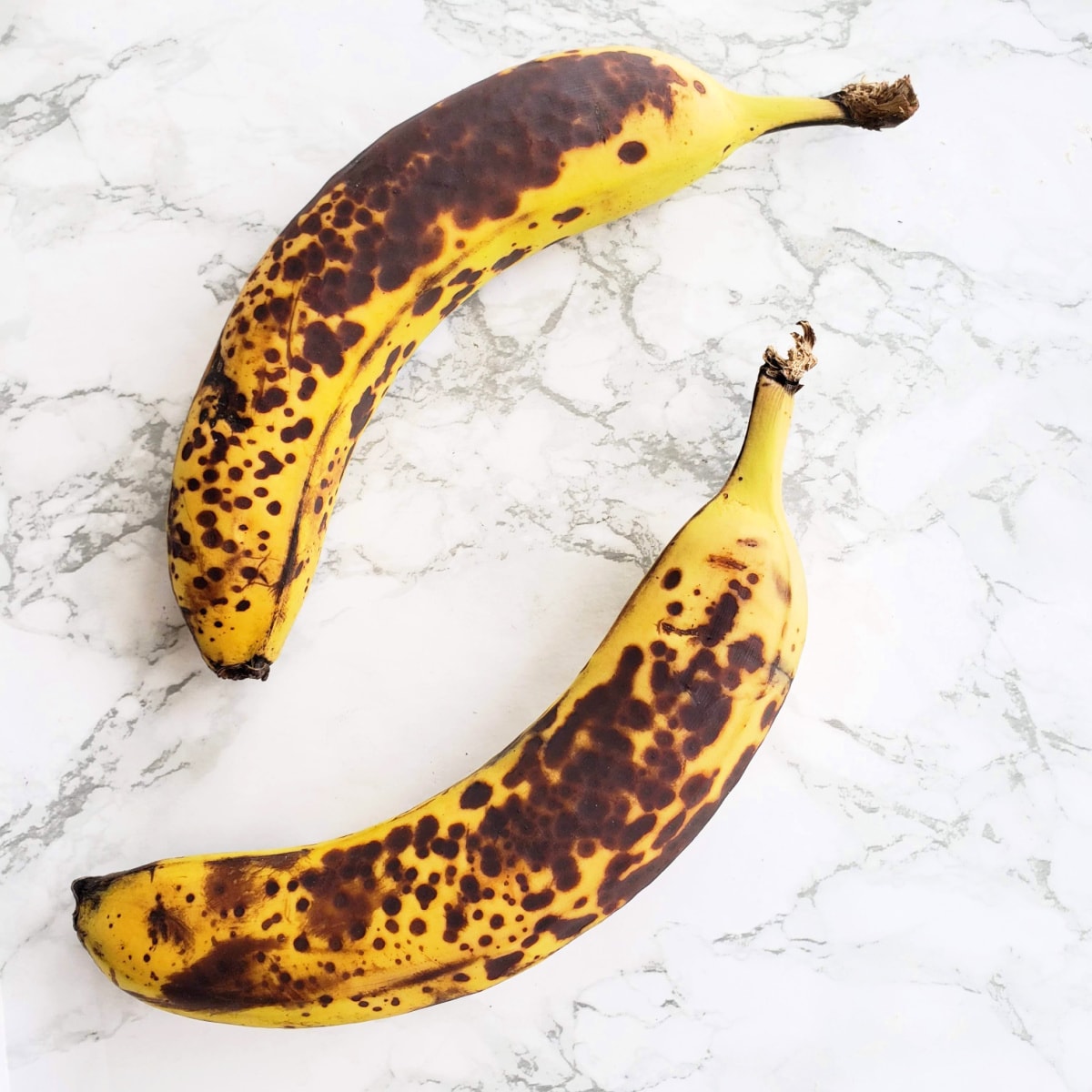 2 speckled ripe bananas on a white marble counter on ShockinglyDelicious.com