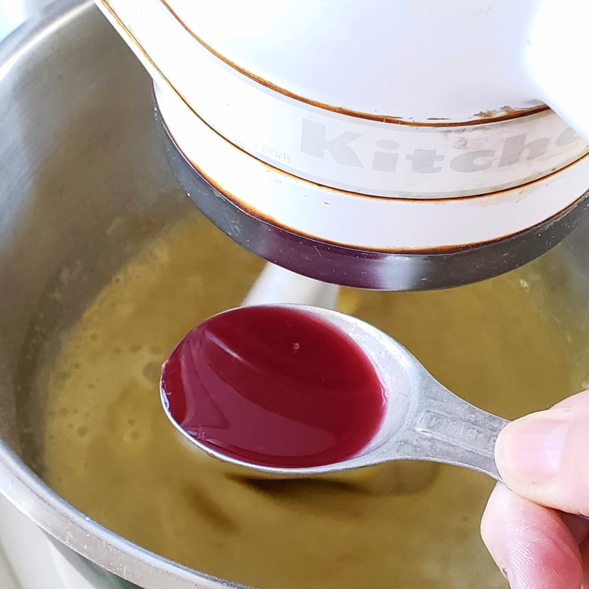 Blood orange juice in a measuring spoon being added to cake batter