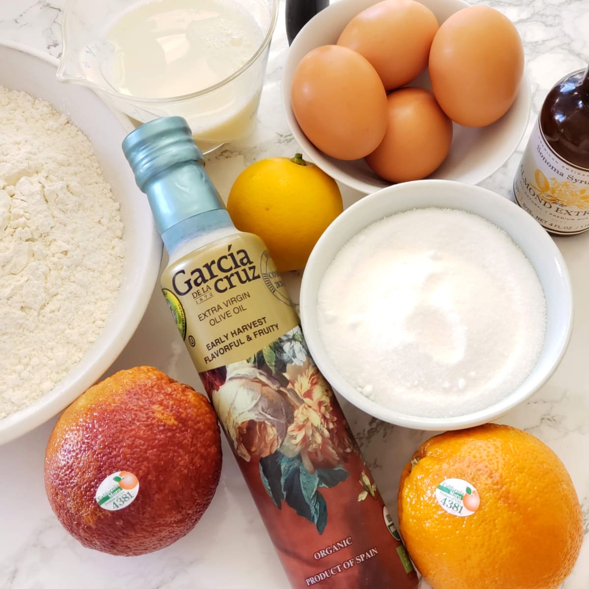 Ingredients for Italian Blood Orange Olive Oil Bundt Cake on a white marble counter