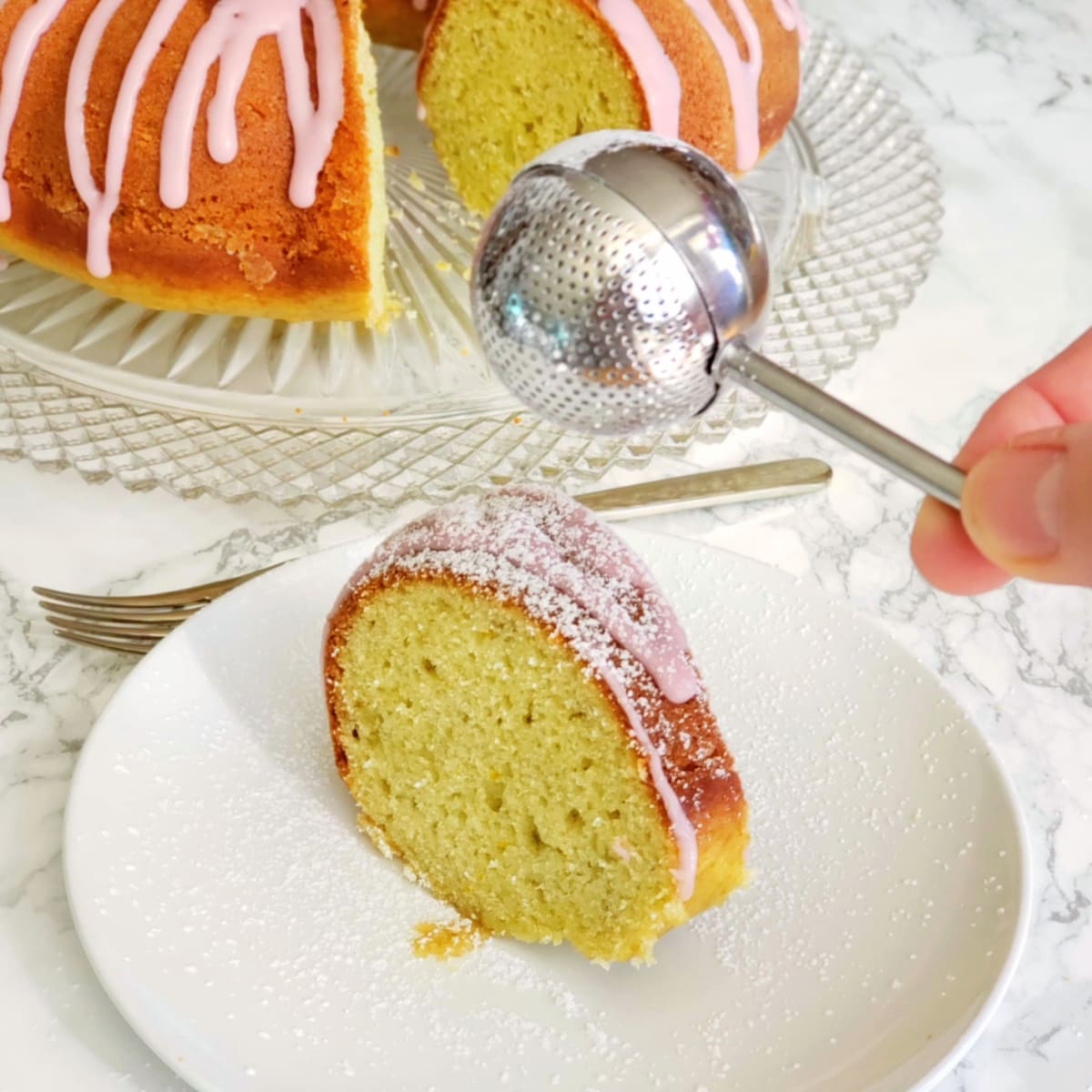 Powdered sugar dusting onto a slice of Italian Blood Orange Olive Oil Bundt Cake