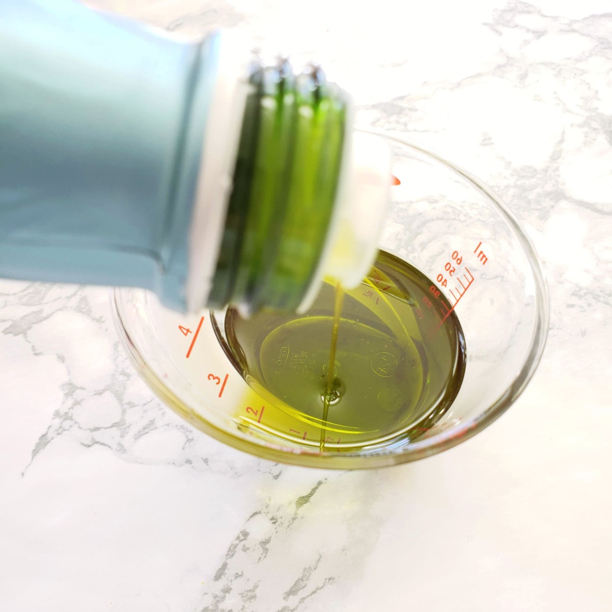 olive oil pouring into a measuring cup