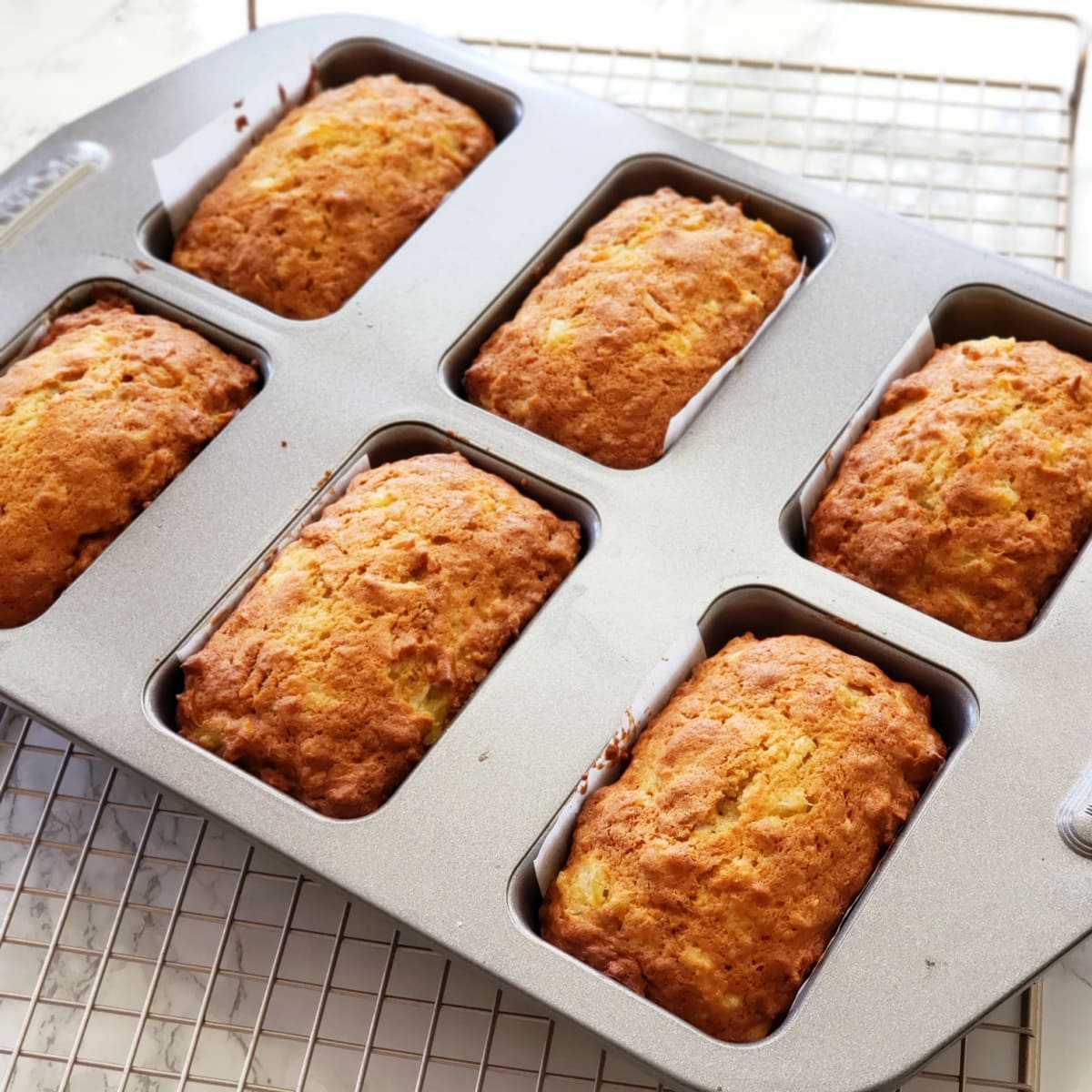 6 Baked loaves in the silver mini loaf pan on a wire rack