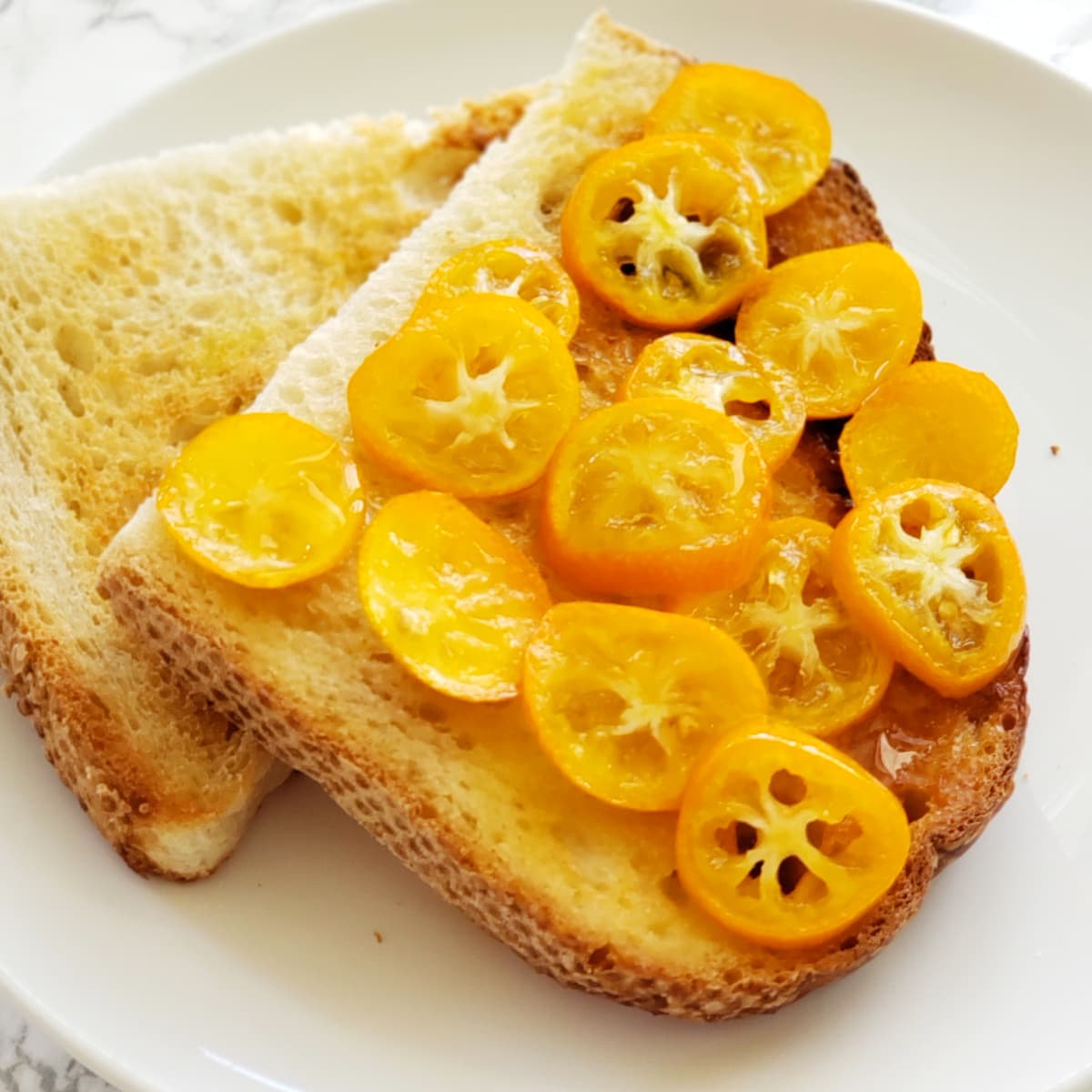 Candied Kumquats on sourdough toast on a white plate