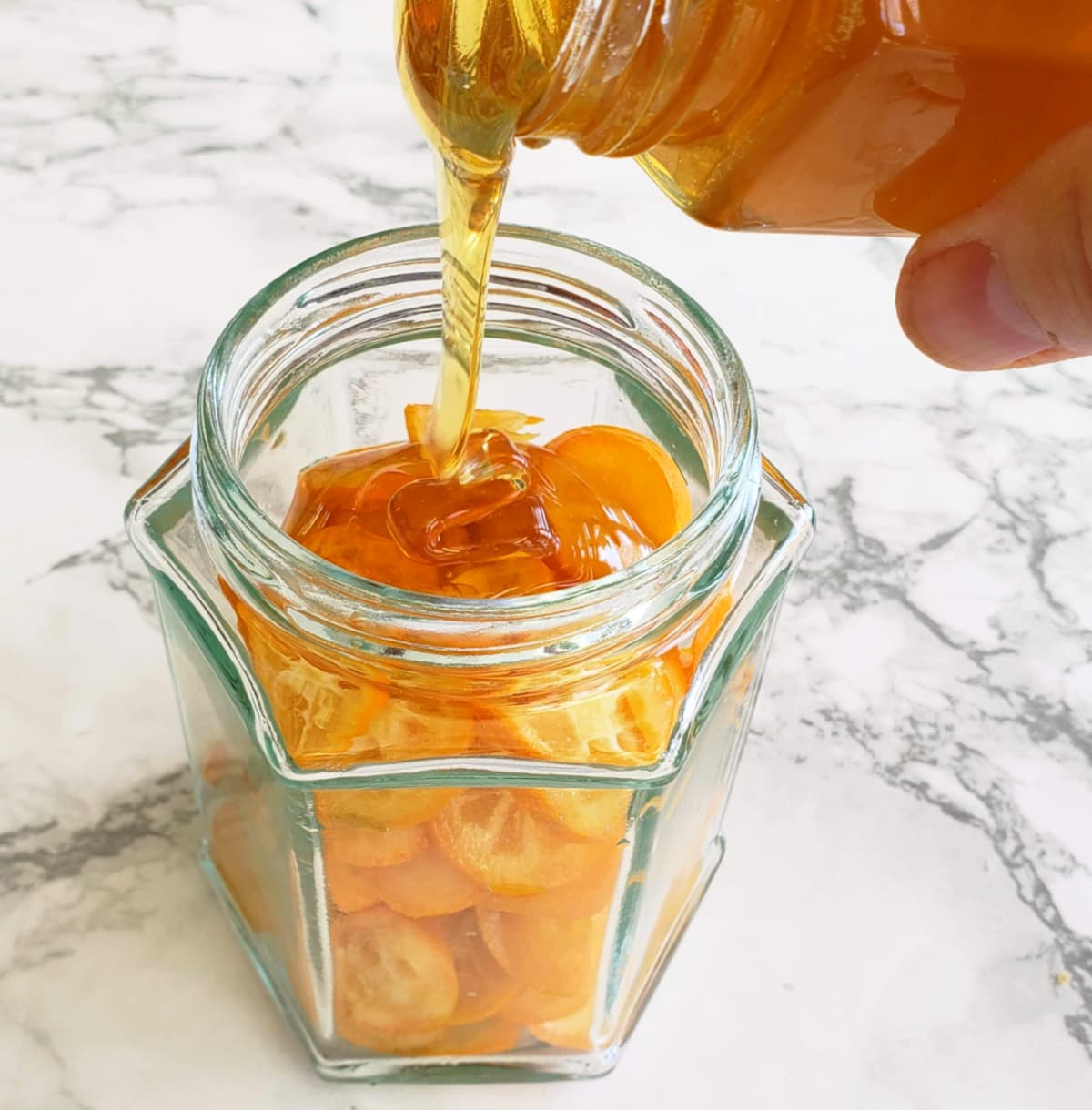 Pouring honey into kumquats in jar