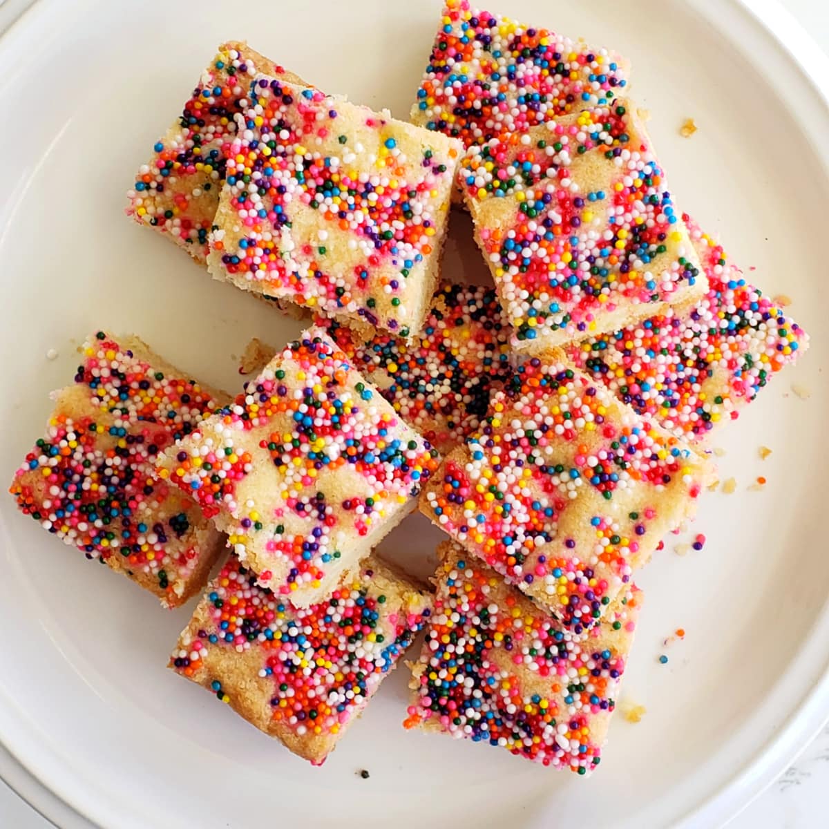 Simple Lemon Shortbread with Sprinkles piled on a white plate on ShockinglyDelicious.com