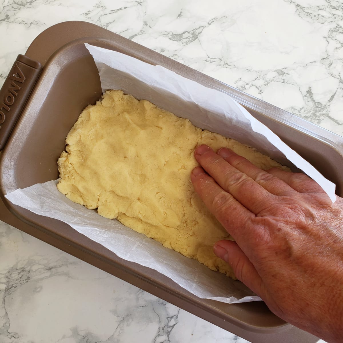 Use your hand to press the shortbread dough into the pan