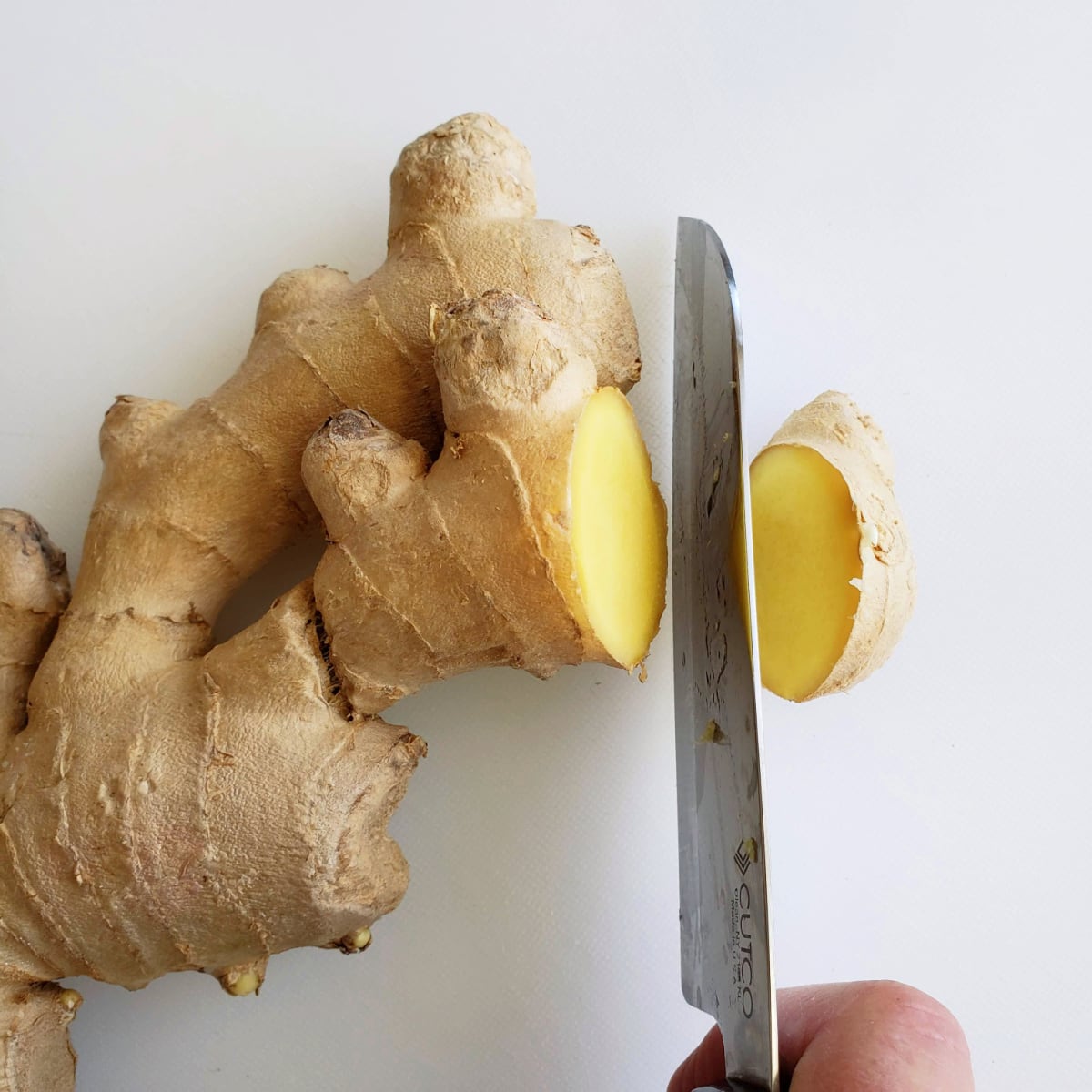 Cut ginger into coins on a white cutting board