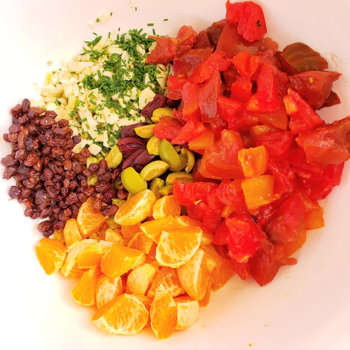 Toss the vegetables and fruits for Pasta with Tomatoes and Tangerines into a white mixing bowl