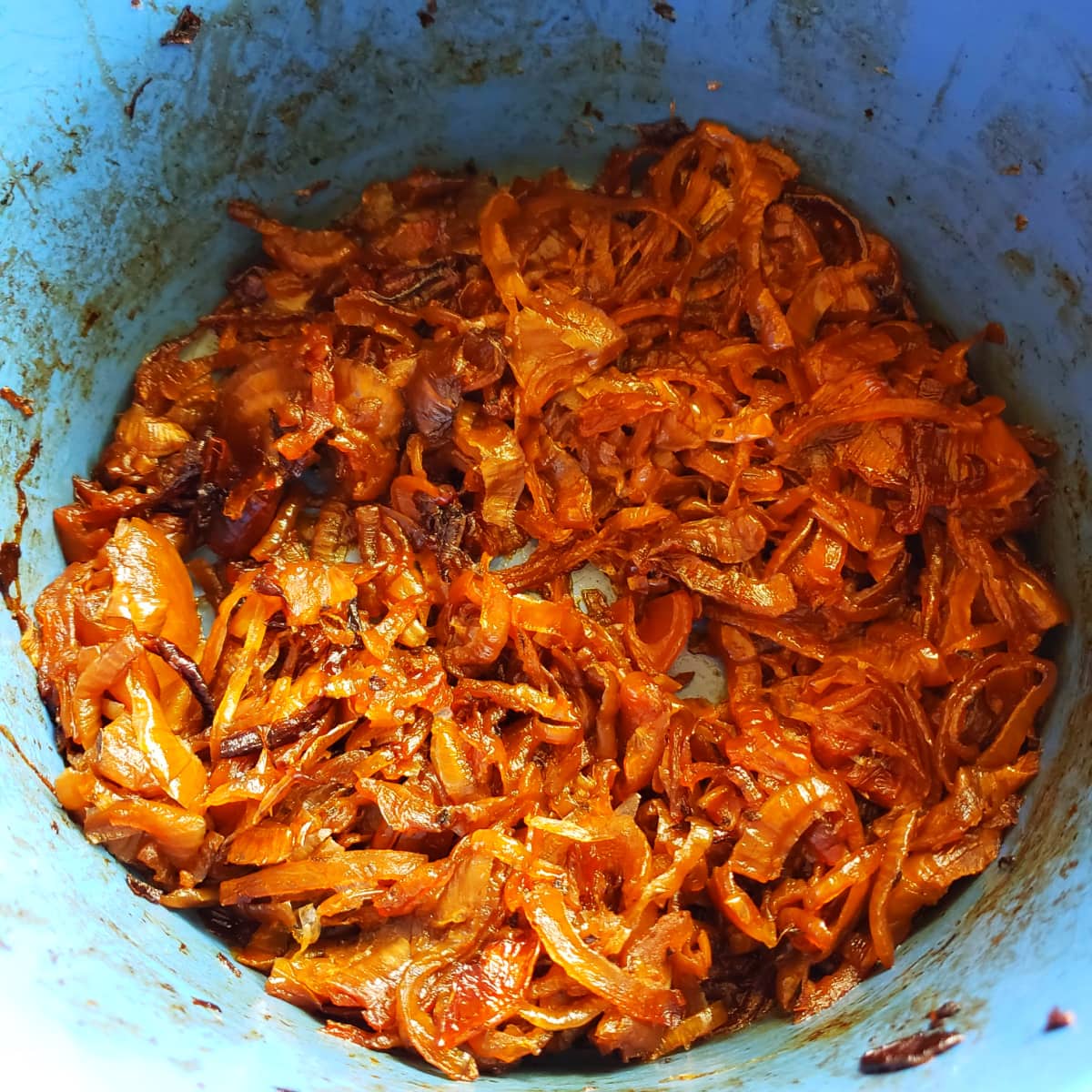 Caramelized onions in a blue crock in the slow cooker on ShockinglyDelicious.com