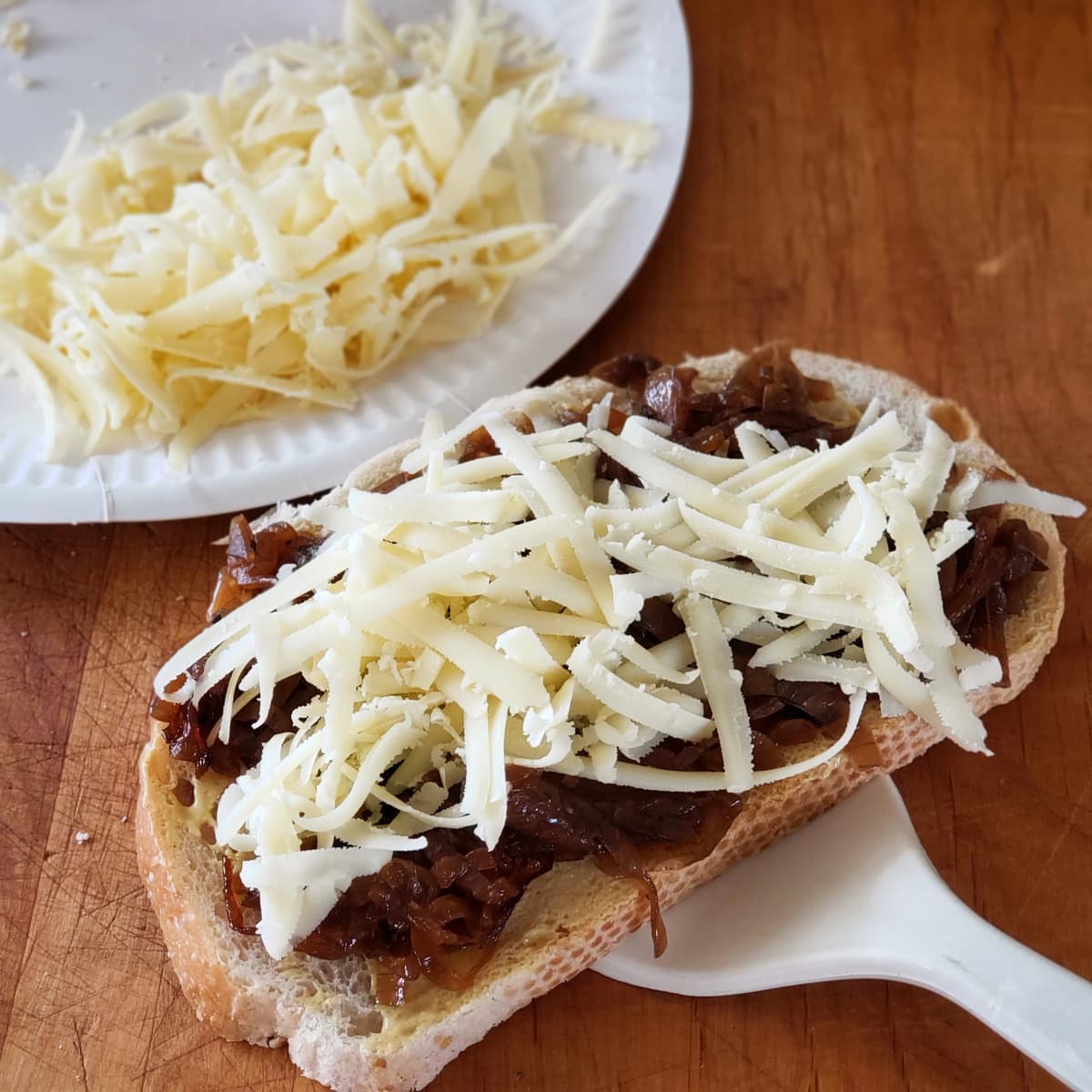 Onions and cheese on a slice of sourdough bread with a spatula underneath