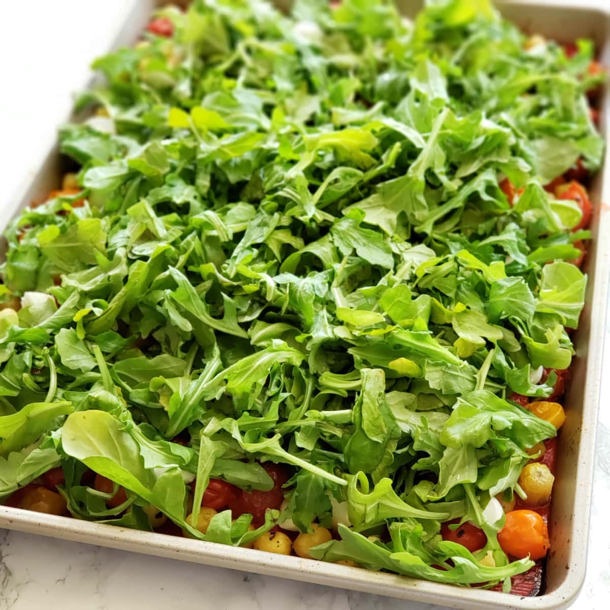 Fresh arugula on top of the hot gnocchi and tomatoes