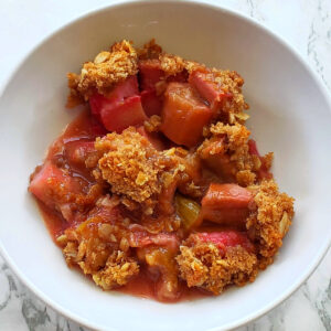 Rhubarb Crumble in a white bowl on a white marble counter on ShockinglyDelicious.com