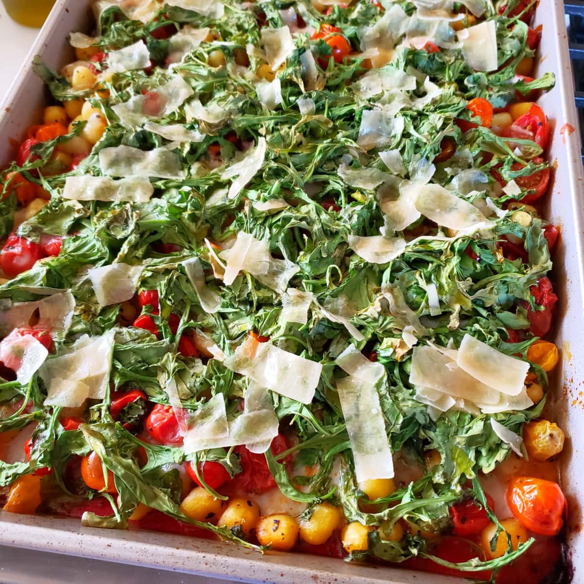 Shaved Parmesan melting on top of the wilted arugula