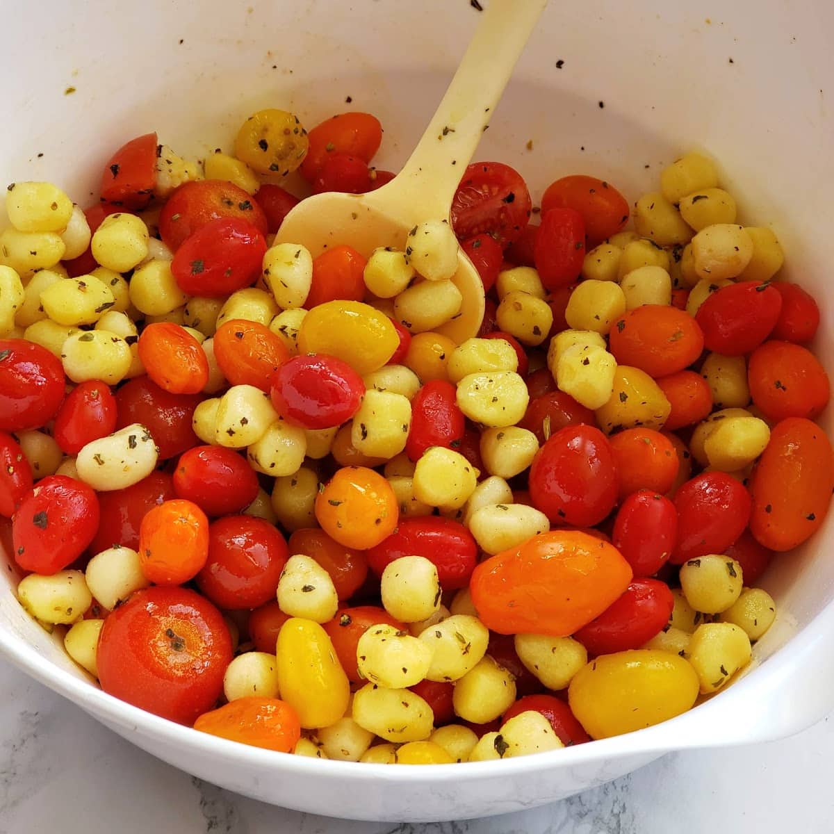 Tomatoes, Gnocchi and seasonings in a white mixing bowl