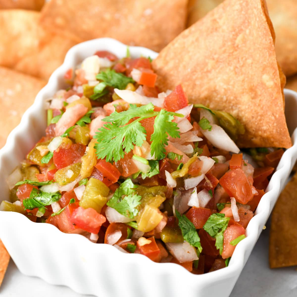 Hatch Pepper Pico De Gallo in a white ramekin surrounded by tortilla chips recipe on ShockinglyDelicious.com