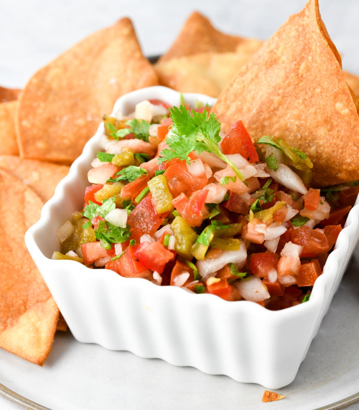 Hatch Pepper Pico De Gallo in a white square bowl with chips in the background on ShockinglyDelicious.com