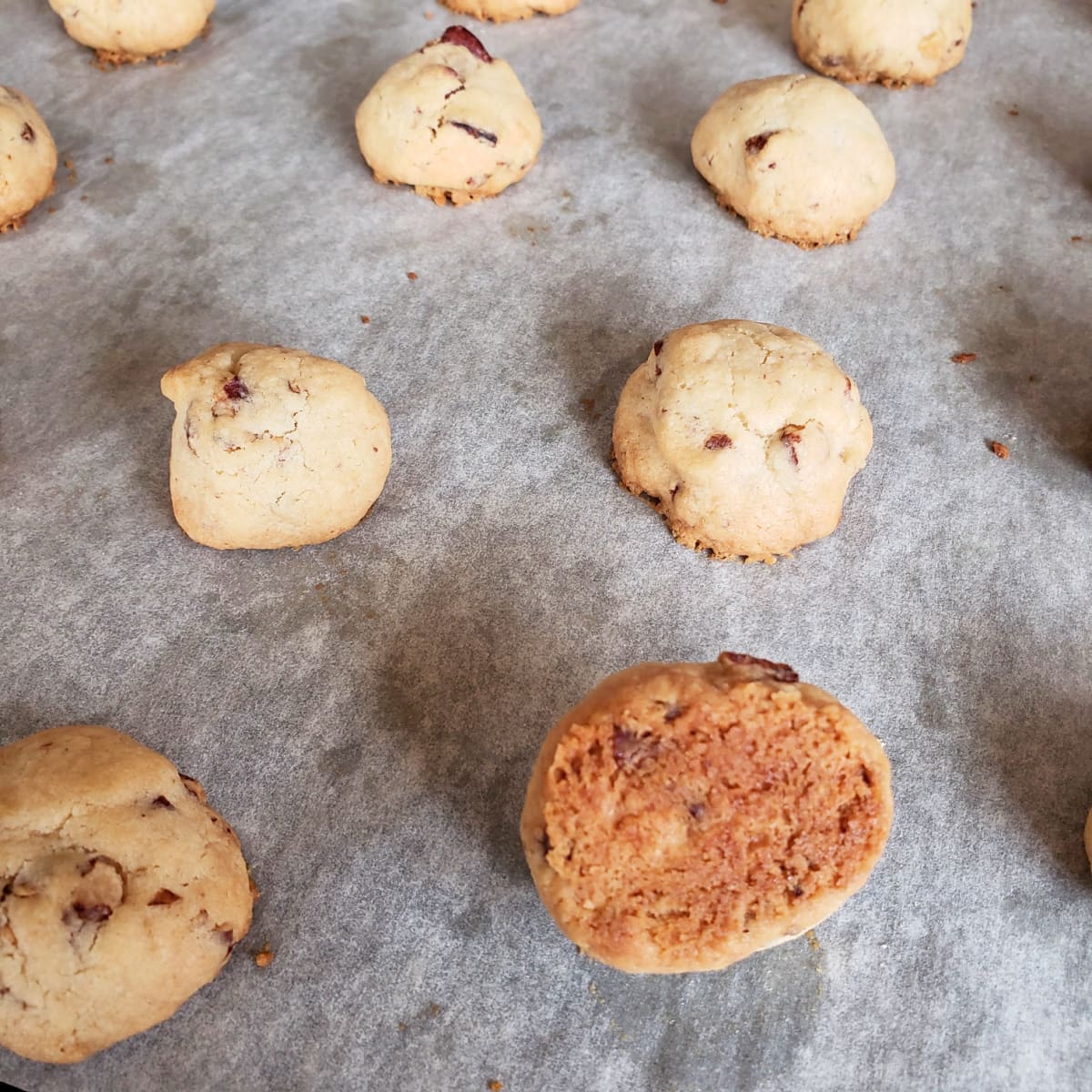 Baked Mexican Wedding Cookies on a baking sheet, with 1 cookie turned upside down to show its bottom