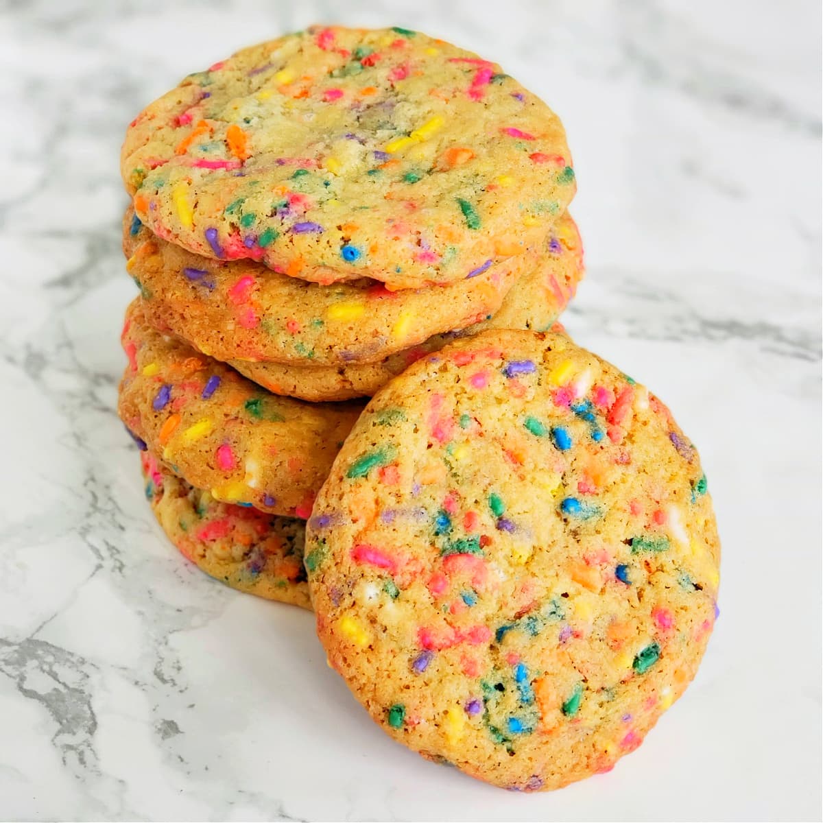 A stack of 6 Confetti Sprinkle Cookies on a white marble counter