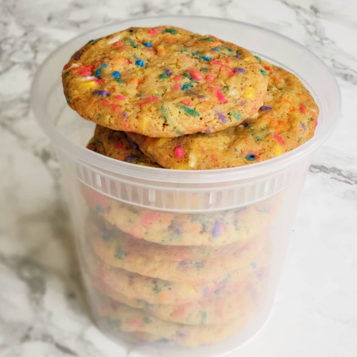 Cookies packed into a takeout container sitting on a white marble counter