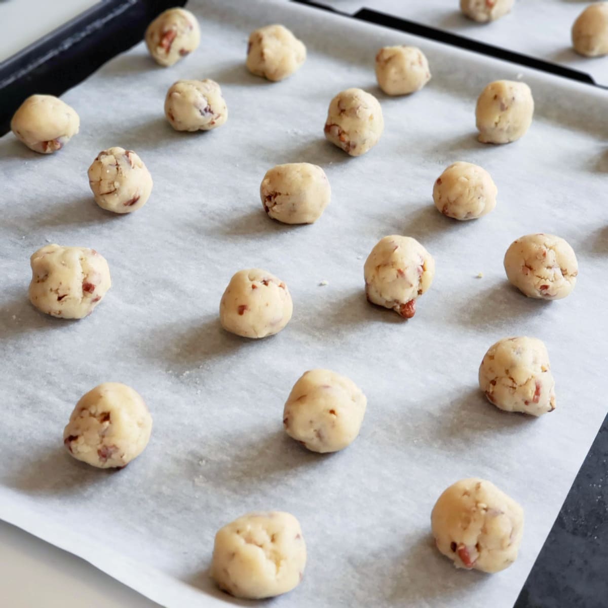 20 dough balls for Mexican Wedding Cookies on a parchment-lined baking sheet