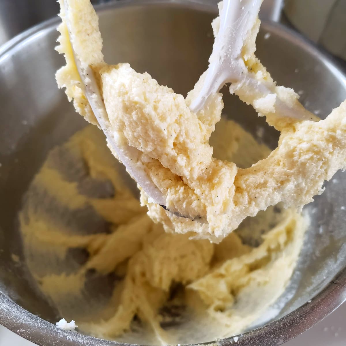 Dough for Confetti Sprinkle Cookies on a white beater in a silver mixing bowl