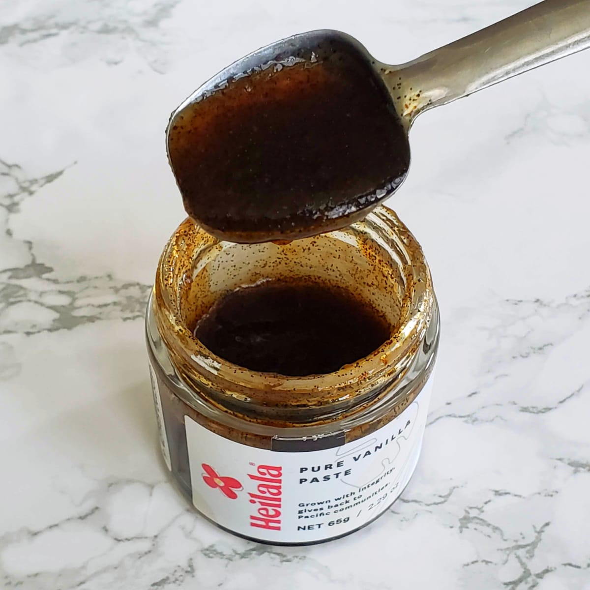 Heilala Vanilla Paste in a jar with a measuring spoon showing it