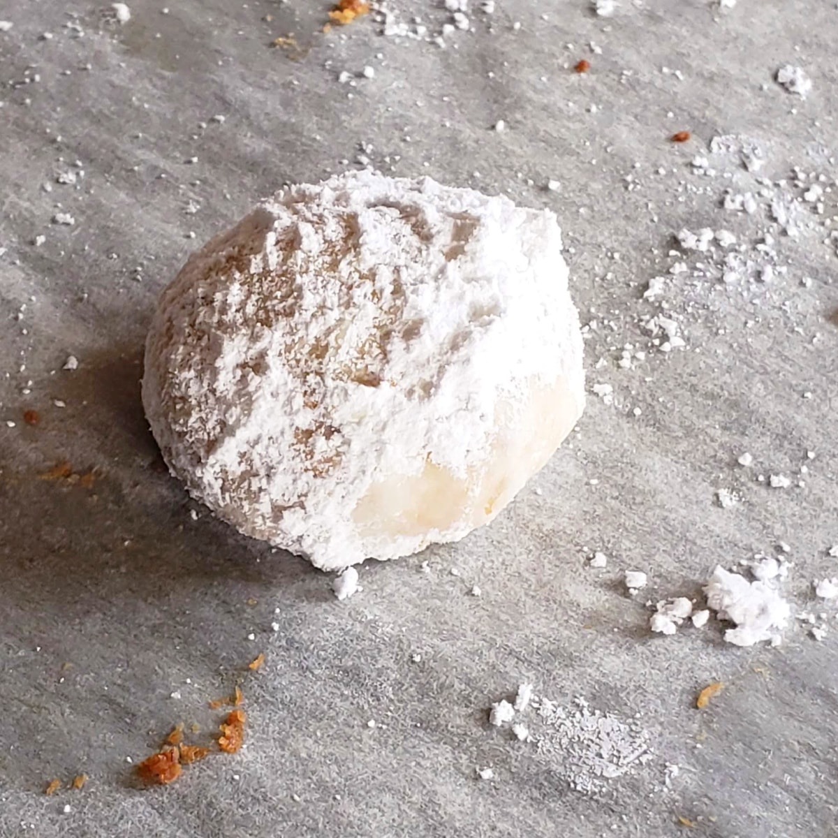 White Mexican Wedding Cookie covered in powdered sugar on a parchment-lined baking sheet