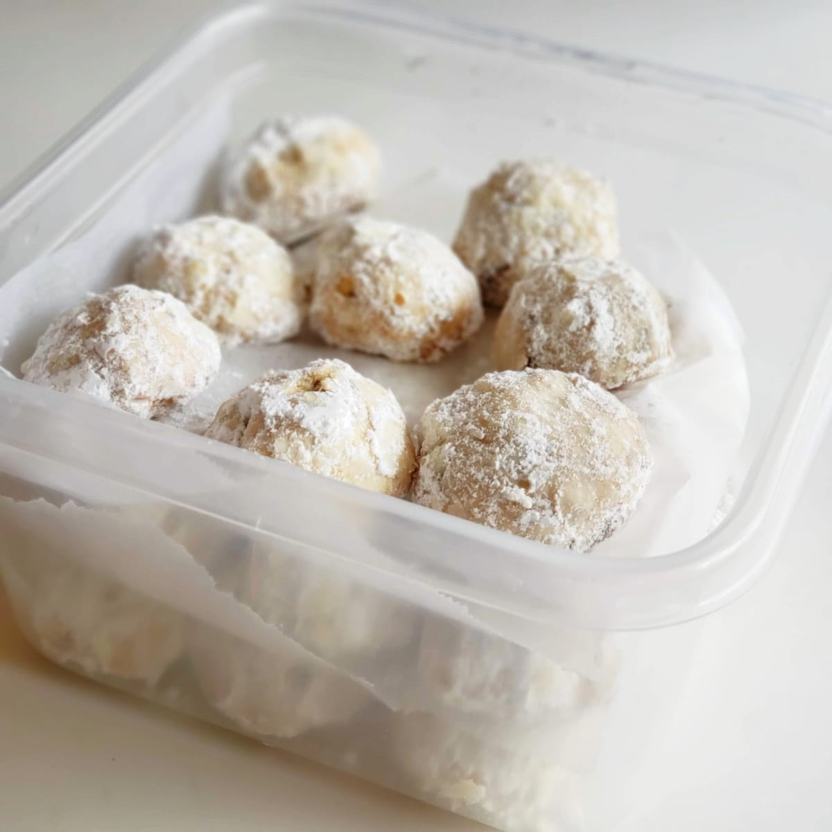 Mexican Wedding Cookies packed into a square plastic storage container on ShockinglyDelicious.com