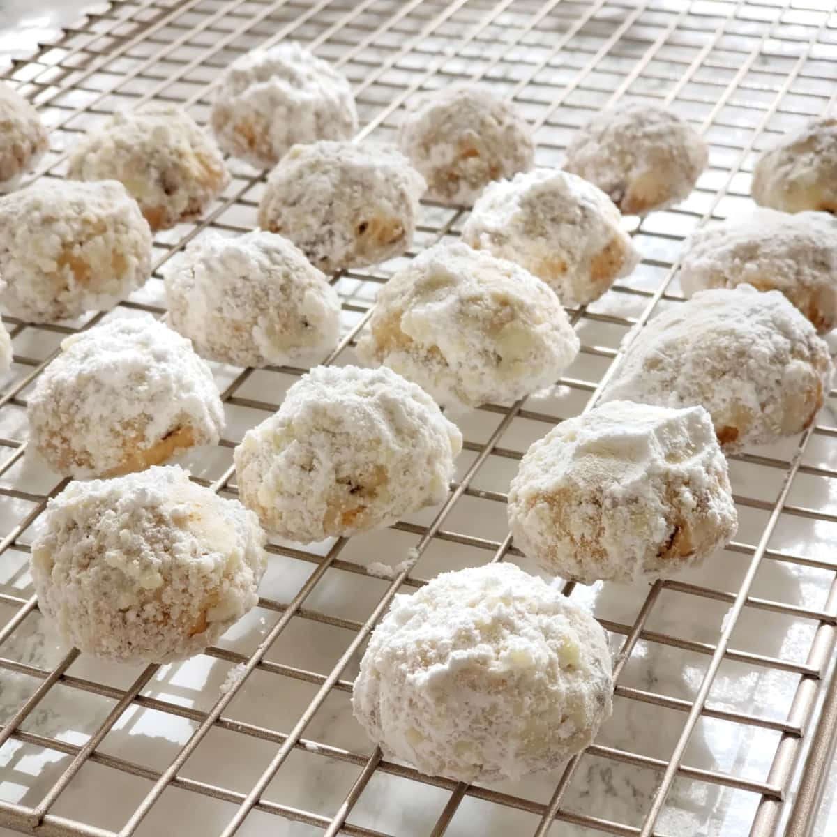 Rows of Mexican Wedding Cookies sit on a cooling rack on ShockinglyDelicious.com