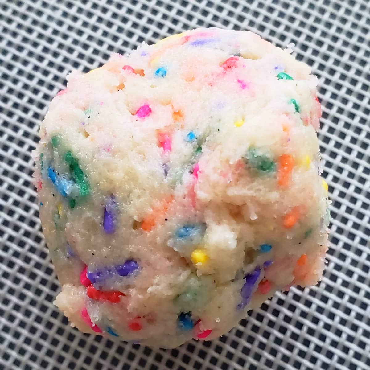 Cookie dough embedded with lots of colorful sprinkles and placed on a silicone liner 20 cookies