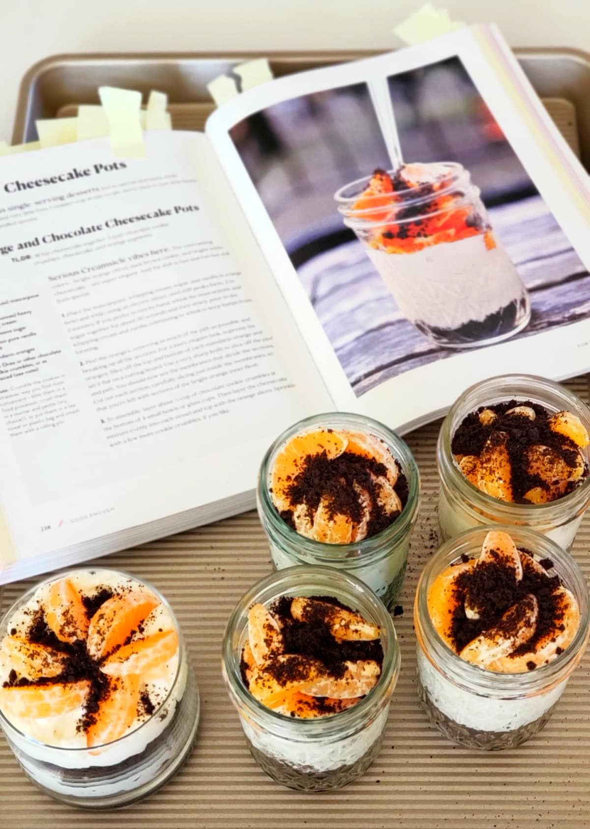 5 desserts on a cookie sheet with an open cookbook alongside