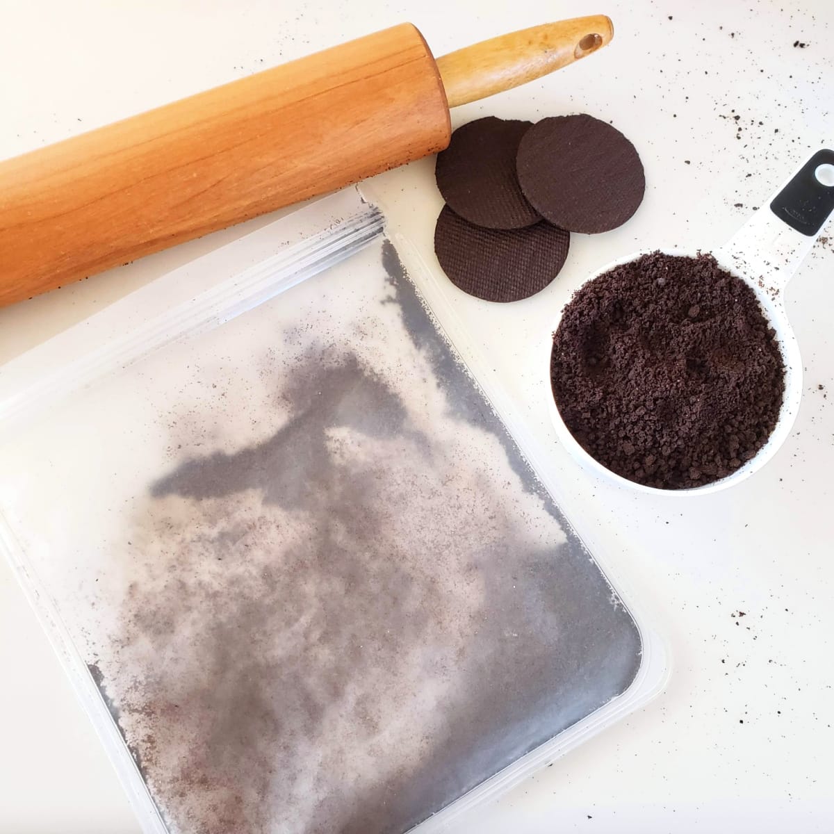 Chocolate wafers being crushed in a plastic bag with a rolling pin at the top