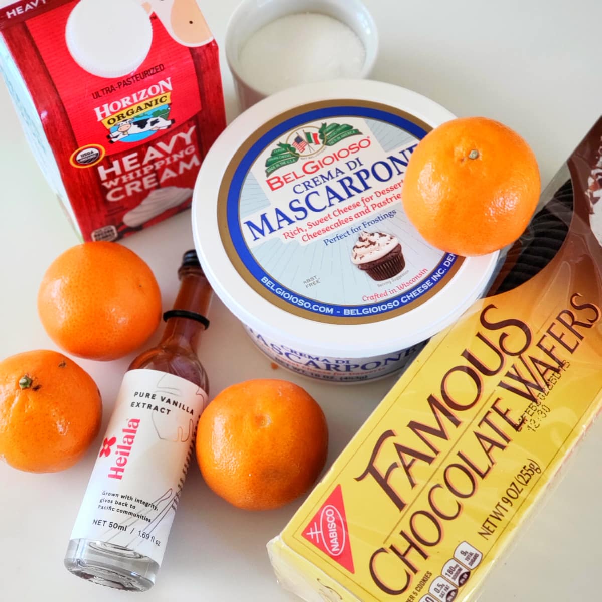 Ingredients for Orange Chocolate Cheesecake Pots on a white counter on ShockinglyDelicious.com