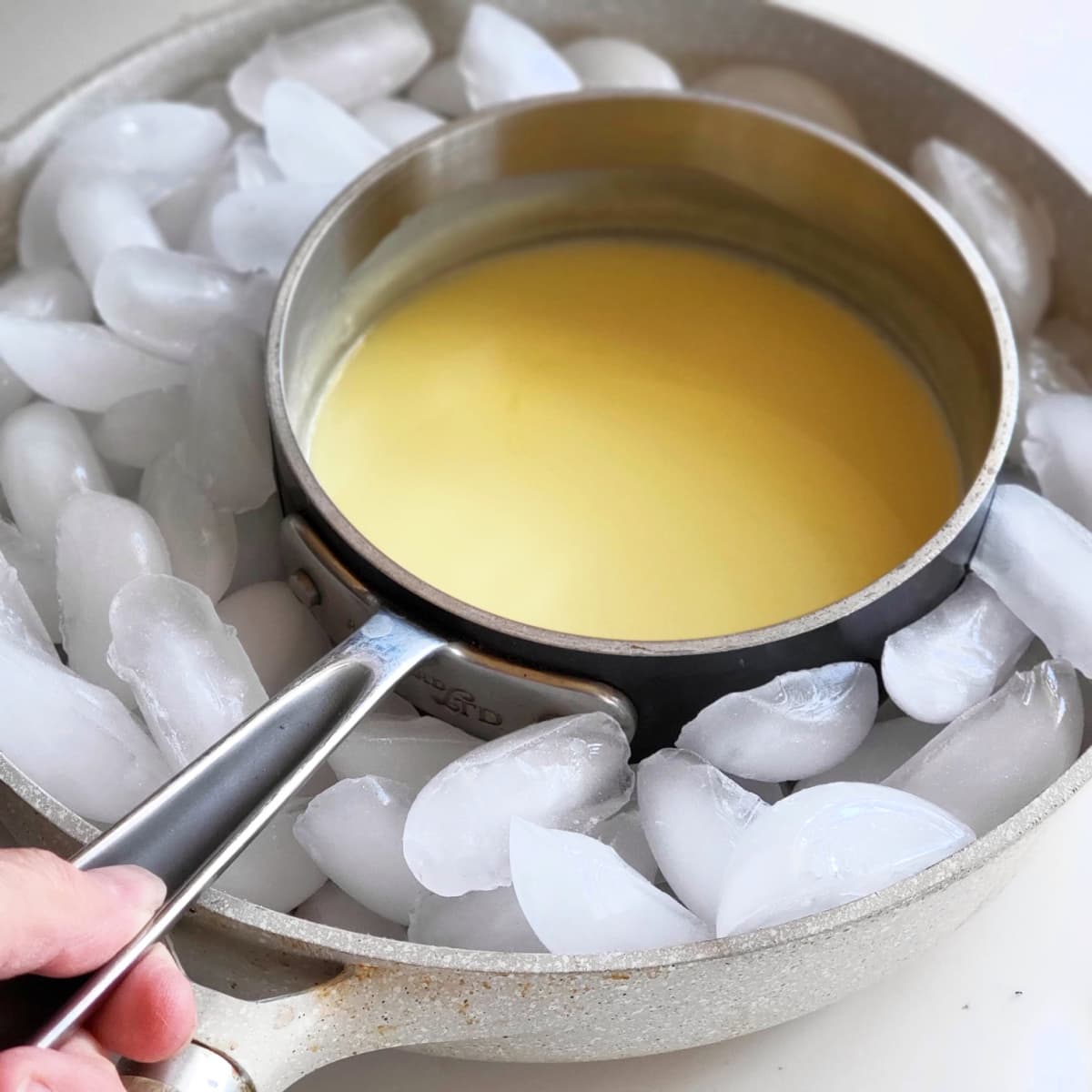 Meyer Lemon Posset in a silver saucepan sits in a skillet filled with ice cubes