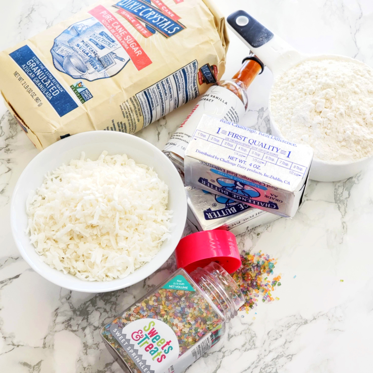 Multiple baking ingredients for Coconut Lime Shortbread laid on a white marble counter on ShockinglyDelicious.com