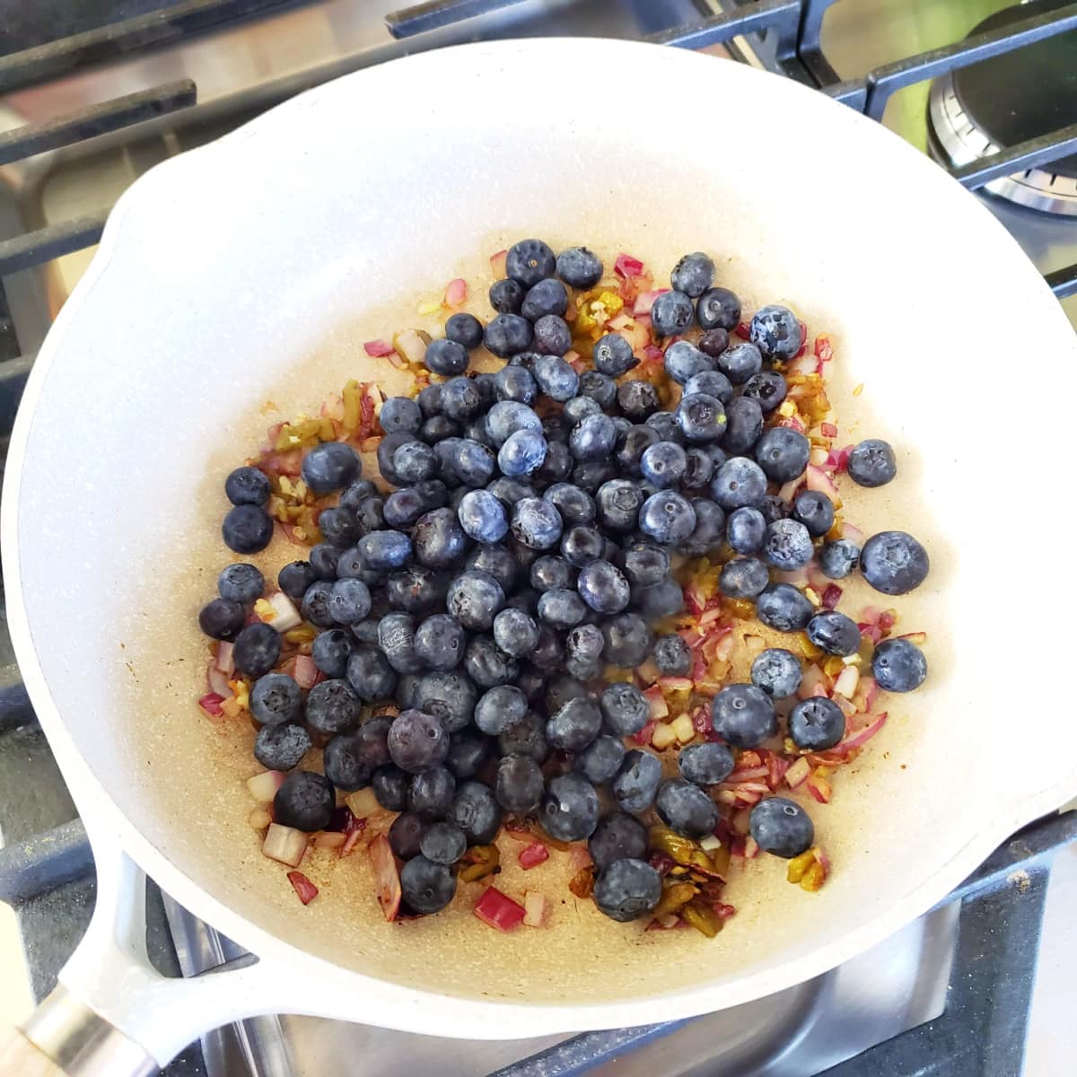 Blueberries in a white skillet on a cooktop
