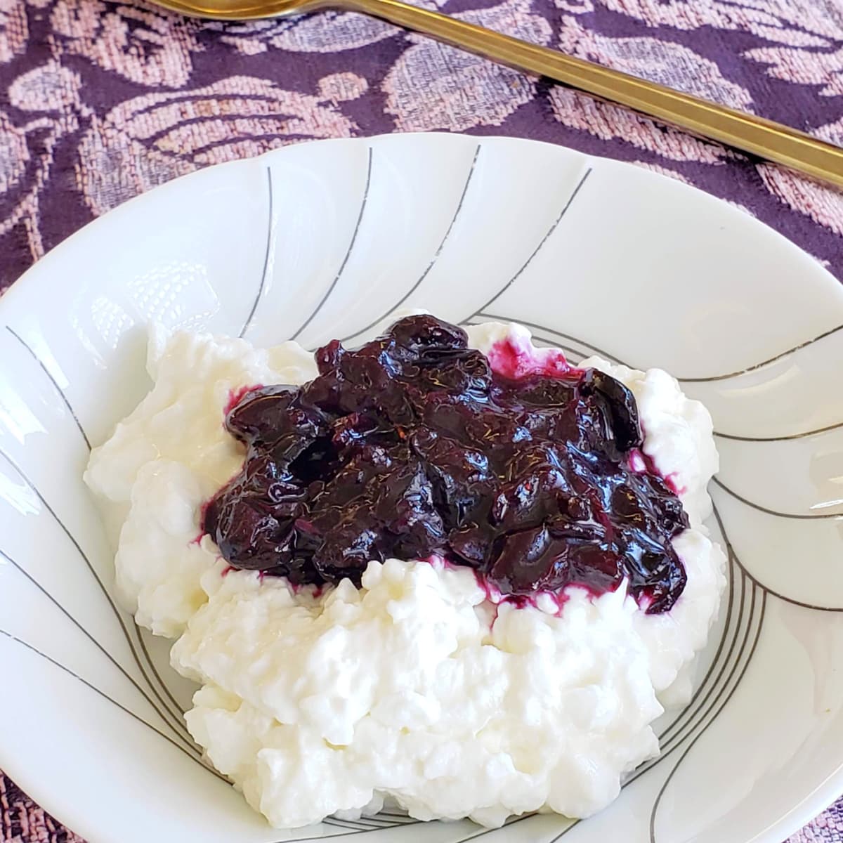 Blueberry Hatch Chile Chutney on cottage cheese in a white bowl on a purple brocade placemat