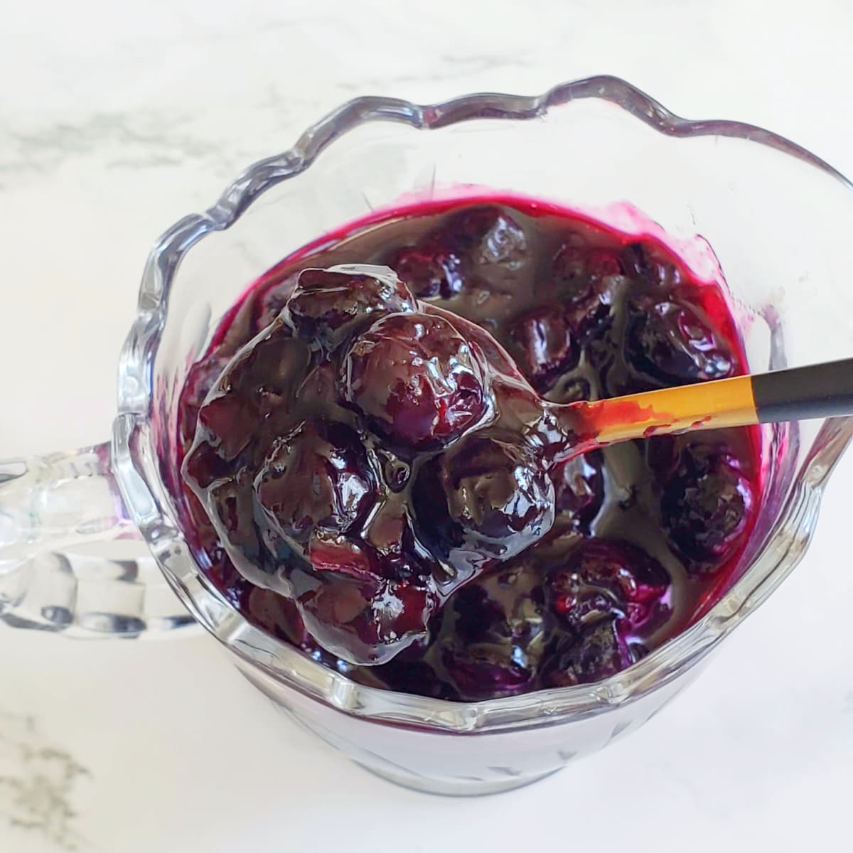 Blueberry Hatch Chile Chutney in a small glass pitcher with a spoon stuck in it