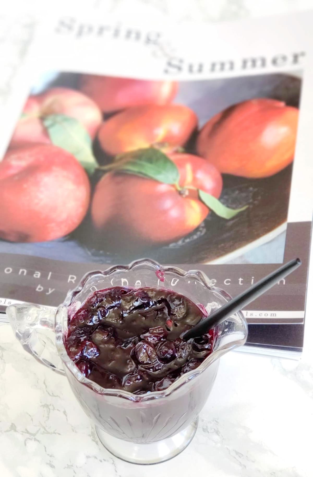 Glass pitcher of Blueberry Chutney in foreground with magazine in background