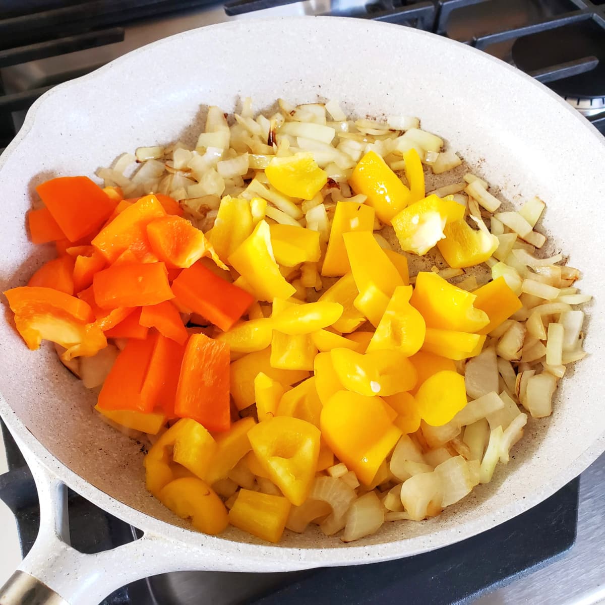 Onions and peppers in a light skillet on ShockinglyDelicious.com