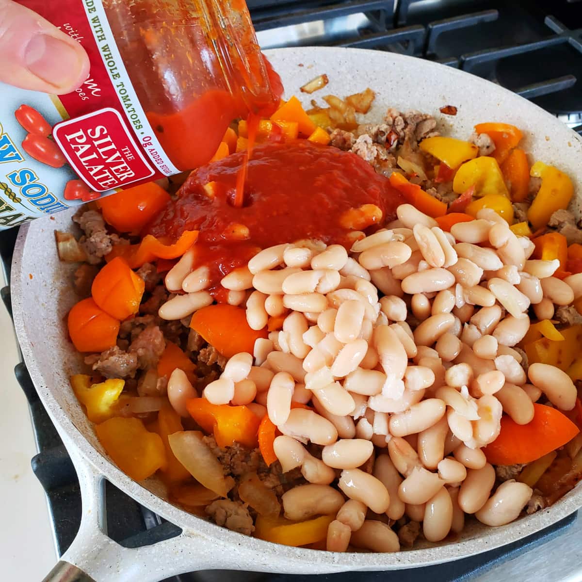 Pouring marinara sauce and beans into the skillet for Pizza Chili on ShockinglyDelicious.com